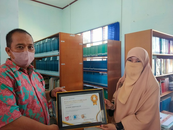 Kepala sekolah SMP Negeri 1 Sangatta Selatan Juliansyah dan Husni pengelola perpustakaan Sekolah menunjukkan Piagam Penghargaan Sekolah Aktif Literasi Nasional